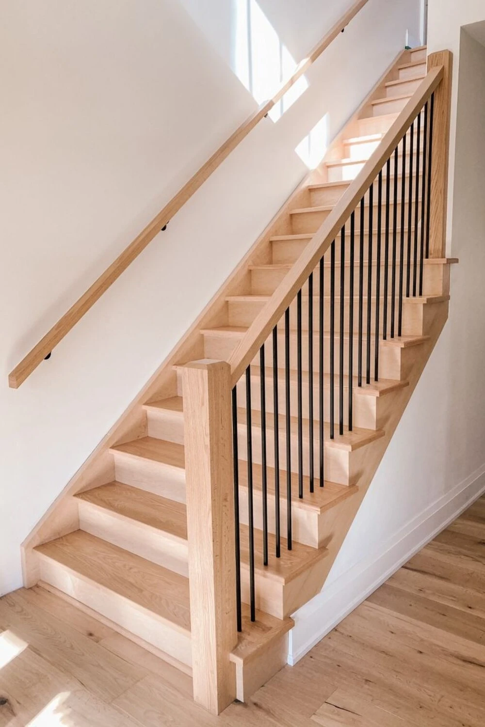 a staircase with oak wood stair railing and an empty wall