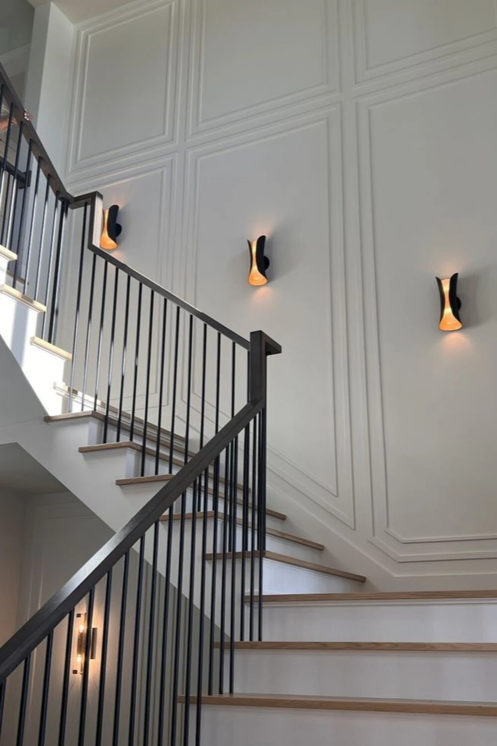 a staircase wall decorated with sculptural wall sconces